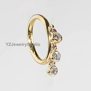 May include: Gold hoop earring with a dangling chain of four clear round gemstones.