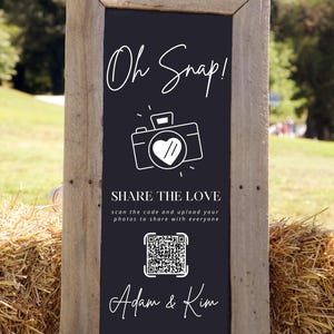 Peut inclure: Panneau de tableau noir encadré de bois rustique avec l'inscription "Oh Snap!" en écriture blanche. En dessous, une icône d'appareil photo avec un cœur et le texte "SHARE THE LOVE". Comprend un code QR et les noms "Adam & Kim".