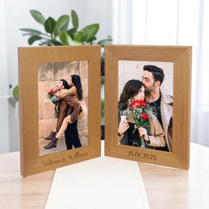 May include: Two wooden photo frames, each holding a photograph of a couple. The frames are light brown and have a simple design. One frame has the inscription "Victoria & William" and the other has the date "25.06.2025" engraved on the bottom.