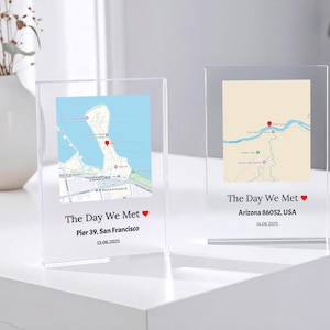 May include: Two clear acrylic photo frames with maps and the text "The Day We Met" and a heart symbol. One frame shows Pier 39, San Francisco, and the other shows Arizona 86052, USA. The dates are displayed below the locations.