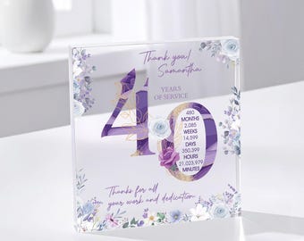 May include: A clear acrylic block with a purple and gold design, celebrating 40 years of service. The block features floral accents, the text "Thank you! Samantha," and a breakdown of service time in months, weeks, days, hours, and minutes.