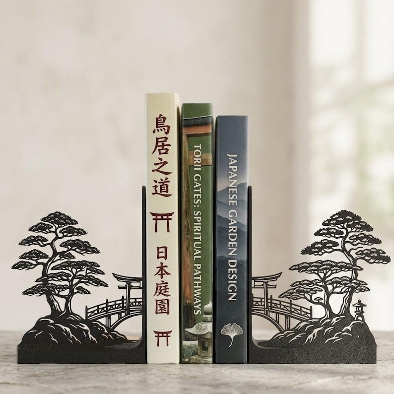 Puede incluir: Un par de sujetalibros de metal negro con un dise&ntilde;o de silueta de un bons&aacute;i, un puente curvo y una linterna de piedra. Los sujetalibros sostienen tres libros, incluidos Torii Gates: Spiritual Pathways y Japanese Garden Design.