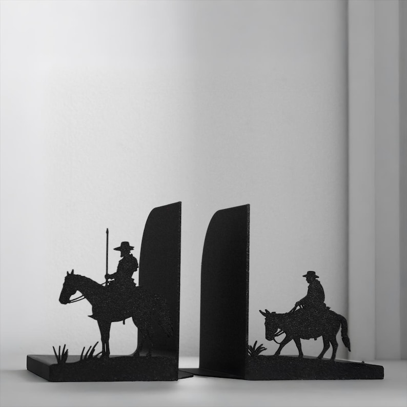 Puede incluir: Un par de sujetalibros de metal negro con siluetas de figuras a caballo. El sujetalibros izquierdo muestra a un jinete con una lanza alta sobre un caballo, mientras que el derecho muestra a un jinete sobre un burro. Ambos tienen acabado texturizado.