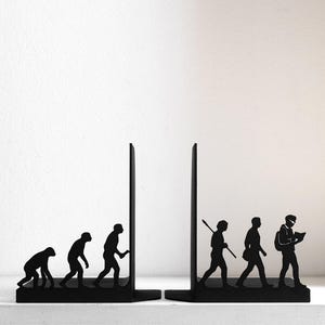 May include: A pair of black metal bookends featuring a silhouette design of human evolution. The left piece shows early hominids progressing towards an upright stance, while the right piece depicts a hunter, a modern human, and a person reading a book.