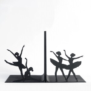 May include: Black metal bookends featuring silhouettes of ballerinas in various dance poses. The bookends have a rectangular base and a vertical support, with the dancers' forms cut out. The design is minimalist and elegant.
