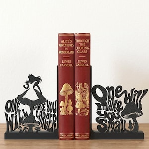 Puede incluir: Dos sujetalibros de metal negro con siluetas de Alicia y setas con el texto One Will Make You Larger y One Will Make You Small, que sostienen dos libros de tapa dura rojos titulados Alice's Adventures in Wonderland y Through the Looking-Glass.