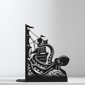 Puede incluir: Un sujetalibros de metal negro con una silueta cortada a l&aacute;ser de un barco de vela siendo enredado por los tent&aacute;culos de un pulpo grande. El dise&ntilde;o incluye olas detalladas en la base y m&aacute;stiles con banderas hacia la esquina superior.