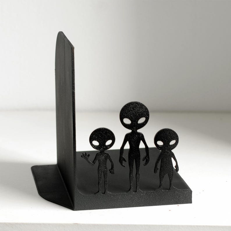 Puede incluir: Sujetalibros negros con forma de familia alien&iacute;gena. Los sujetalibros presentan tres figuras de alien&iacute;genas estilizadas sobre una base rectangular. Fabricados en material negro, est&aacute;n dise&ntilde;ados para mantener los libros en posici&oacute;n vertical.