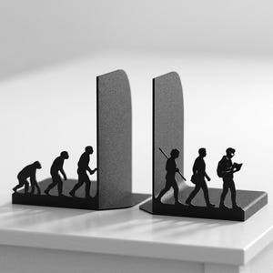 May include: A pair of black metal bookends featuring a silhouette design of human evolution. The left piece shows early hominids progressing to an upright stance, while the right piece depicts modern humans with tools, a bag, and a book.