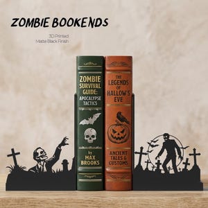 Puede incluir: Soportes para libros de zombis de metal negro con acabado mate. Los sujetalibros presentan un dise&ntilde;o de silueta de zombi con l&aacute;pidas y el texto "ZOMBIE BOOKENDS". Dos libros se sujetan en su lugar, uno verde y otro marr&oacute;n, con los t&iacute;tulos "ZOMBIE SURVIVAL GUIDE" y "THE LEGENDS OF HALLOW'S EVE".
