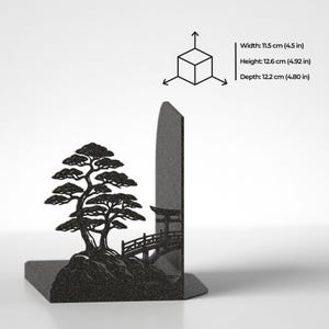 Puede incluir: Un sujetalibros de metal negro con la silueta de un bons&aacute;i y un peque&ntilde;o puente. Las dimensiones indicadas son 11,5 cm de ancho, 12,6 cm de alto y 12,2 cm de profundidad, junto a un diagrama de cubo con flechas.