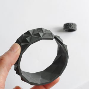 May include: A white ceramic mug with a black handle and the text "But First, Coffee" in a black, handwritten-style font. The mug is on a white surface.