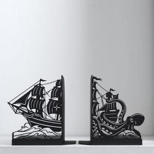 Puede incluir: Un par de sujetalibros de metal negro con tem&aacute;tica n&aacute;utica. La pieza izquierda representa un velero sobre olas, mientras que la derecha muestra un pulpo grande con tent&aacute;culos envolviendo un segundo velero entre olas turbulentas.