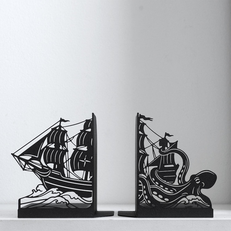 Puede incluir: Un par de sujetalibros de metal negro con tem&aacute;tica n&aacute;utica. La pieza izquierda representa un velero sobre olas, mientras que la derecha muestra un pulpo grande con tent&aacute;culos envolviendo un segundo velero entre olas turbulentas.