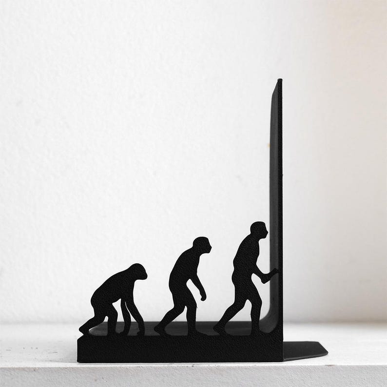 May include: A black metal bookend featuring a silhouette of the human evolution process, starting with a primate figure on all fours and progressing to an upright human figure reaching towards the vertical edge of the bookend structure.