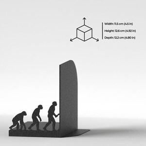 May include: A black metal bookend featuring a silhouette of human evolution. The product dimensions are listed as 11.5 cm in width, 12.6 cm in height, and 12.2 cm in depth, accompanied by a 3D cube icon with directional arrows.