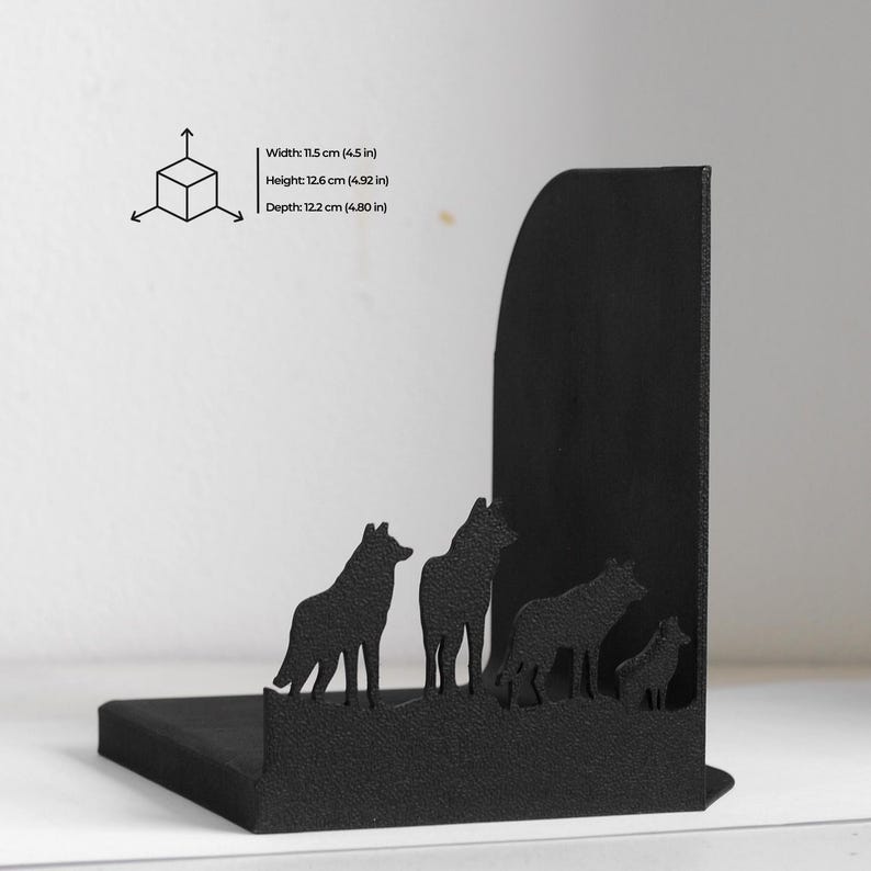 Puede incluir: Un sujetalibros de metal negro con la silueta de cuatro lobos sobre una base. Las dimensiones est&aacute;n impresas como ancho 11,5 cm, alto 12,6 cm y profundidad 12,2 cm junto a un peque&ntilde;o diagrama de cubo con flechas de direcci&oacute;n.