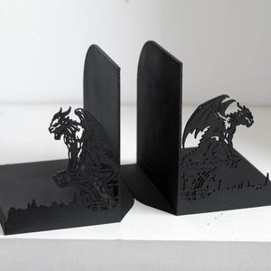 Puede incluir: Par de sujetalibros negros con dise&ntilde;o de g&aacute;rgola g&oacute;tica. Los sujetalibros est&aacute;n hechos de material negro s&oacute;lido y presentan una silueta detallada de una criatura alada posada sobre un paisaje urbano. Est&aacute;n dise&ntilde;ados para mantener los libros en posici&oacute;n vertical.