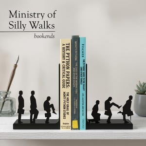 May include: Black metal bookends featuring silhouettes of figures in various silly walking poses. The bookends hold several books with titles like "The Python Papers" and "The Pythons Guide to the Galaxy". The words "Ministry of Silly Walks" are above the bookends.