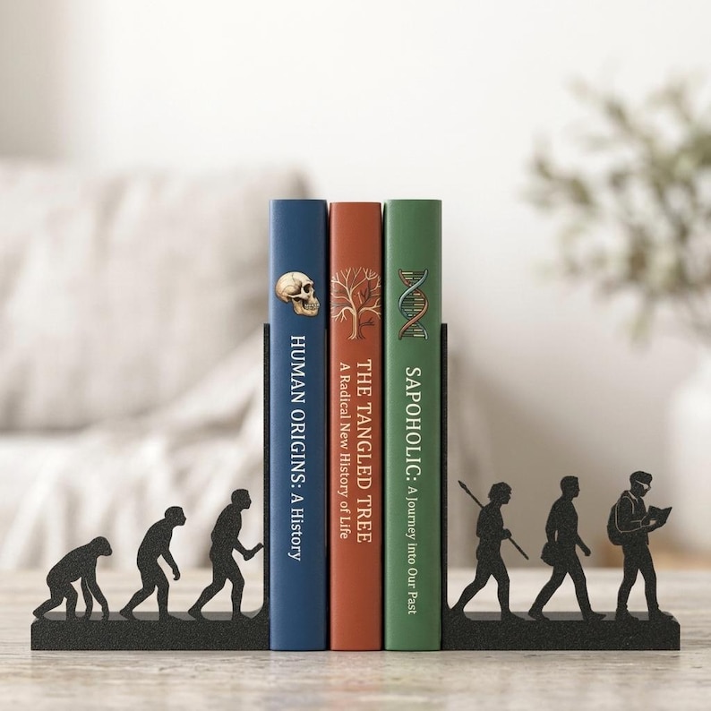 May include: A black metal bookend set featuring a human evolution silhouette design. The left piece shows early hominids, while the right piece depicts modern humans. Three books are placed between them, titled Human Origins, The Tangled Tree, and Sapoholic.