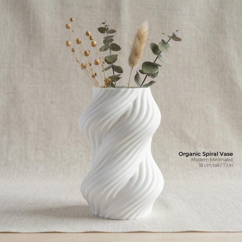 Puede incluir: Un jarr&oacute;n espiral org&aacute;nico blanco con un dise&ntilde;o minimalista moderno. El jarr&oacute;n mide 18 cm de alto y presenta un patr&oacute;n arremolinado texturizado. Flores secas y vegetaci&oacute;n est&aacute;n dispuestas dentro del jarr&oacute;n, agregando un toque natural a la decoraci&oacute;n.