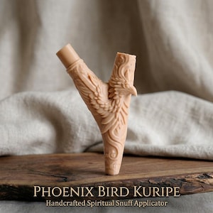 Op de afbeelding: Een beige, Y-vormige applicator met een gebeeldhouwd feniksvogelontwerp. De applicator heeft aan &eacute;&eacute;n uiteinde een cilindrische buis en aan het andere uiteinde een gedetailleerde vogelkop. De tekst "PHOENIX BIRD KURIPIE" en "Handcrafted Spiritual Snuff Applicator" staan onderaan.