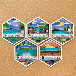 May include: Five hexagonal stickers with illustrations of Manitoulin Island, Canada. Each sticker depicts a different location: Little Current, Gore Bay, South Baymouth, Mindemoya, and Providence Bay. The stickers are brightly coloured and feature text labels in a cartoon style.