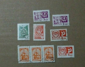 Puede incluir: Una colección de sellos postales soviéticos vintage con varios diseños, incluyendo una estrella roja, una hoz y un martillo, y retratos de personas. Los sellos son de diferentes colores, incluyendo rojo, naranja, verde y morado. Los sellos están en buen estado y han sido cancelados.