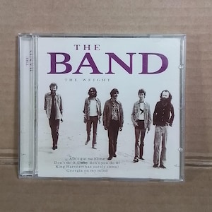 May include: CD case for "The Band" album, "The Weight." The cover features the band members walking on a sandy surface. The band's name is in large purple letters, with the album title below. Song titles are listed at the bottom.