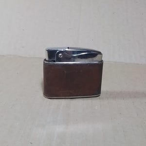 May include: A brown leather-covered lighter with a silver top and a chrome finish.