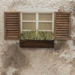 Puede incluir: Un marco de ventana blanco con contraventanas de madera marrón y una jardinera marrón con plantas verdes. La ventana está en una pared blanca texturizada.