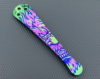 May include: A green, pink and blue titanium pocket clip with a stylised dragon design.