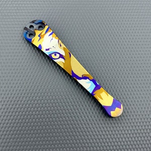 May include: A gold and blue titanium pocket clip with a tiger face design.