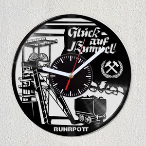 May include: Black and white vinyl record clock featuring a design of a mine shaft, a coal cart, and the text "Glück auf Kumpel!" and "RUHRPOT". The clock face is black with white hands.