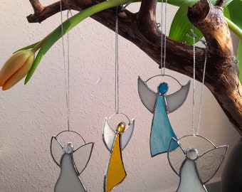 May include: Four stained glass angel ornaments hanging from a branch. The angels are white, blue, yellow, and silver. They are all different sizes and have different details.