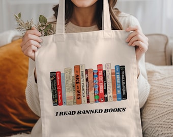 May include: A white canvas tote bag with the text "I READ BANNED BOOKS" printed in black. The bag features a graphic of a bookshelf with the spines of several banned books, including "To Kill a Mockingbird", "A Wrinkle in Time", "The Color Purple", "The Kite Runner", "Harry Potter", "1984", "Bridge to Terabithia", "Of Mice and Men", "Forever", "The Handmaid's Tale", and "The Best of Me".
