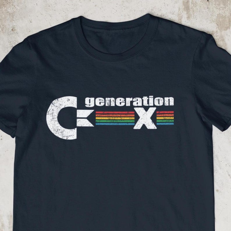 May include: Navy blue t-shirt with a white graphic that reads "generation X". The design includes a stylized "C" and "X" with a rainbow-colored bar in between. The shirt is made of a soft material.