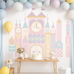 May include: A whimsical party scene with a pastel castle wall decal, balloons, and a cake. The castle features a clock, Mickey Mouse icons, and numbers. A wooden table holds the cake, flowers, and other decorations. Balloons in various colors adorn the background.