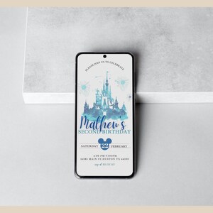 May include: A blue and white watercolor illustration of Cinderella's Castle with fireworks. The text "Mathew's Second Birthday" is in blue with a Mickey Mouse head. The date is Saturday, February 22nd, with a time of 2:00 PM to 7:00 PM. The address is 16385 Main St. Huston, TX 44100.