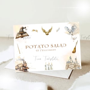 Könnte beinhalten: Eine weiße Karte mit braunem Rand und einer Aquarell-Illustration eines Zaubererhutes, einer Brille, eines goldenen Schnitzers, eines Besens, eines Zuges und eines Schlosses. Der Text "POTATO SALAD GF/VEGETARIAN" ist auf die Karte gedruckt.