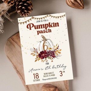 Puede incluir: Una invitación de color blanco y dorado para una fiesta de la calabaza para el sexto cumpleaños de Annie. La invitación presenta una ilustración de acuarela de una calabaza con el número 6, rodeada de hojas de otoño y flores. El texto de la invitación dice "Únete a nosotros para una fiesta de la calabaza para el sexto cumpleaños de Annie" con la fecha y la hora de la fiesta que se indican a continuación.