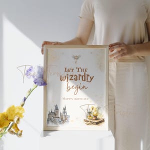 May include: A white printable sign with a gold glitter background and a brown text overlay that reads "Let the wizardry begin" and "Happy Birthday". The sign features a watercolor illustration of Hogwarts castle and a golden key with a dragonfly.