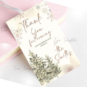 May include: A white thank you card with a winter theme. The card features two stylized trees with white lights and snowflakes. The text on the card reads "Thank you for coming and celebrate our with us, love the Smiths".