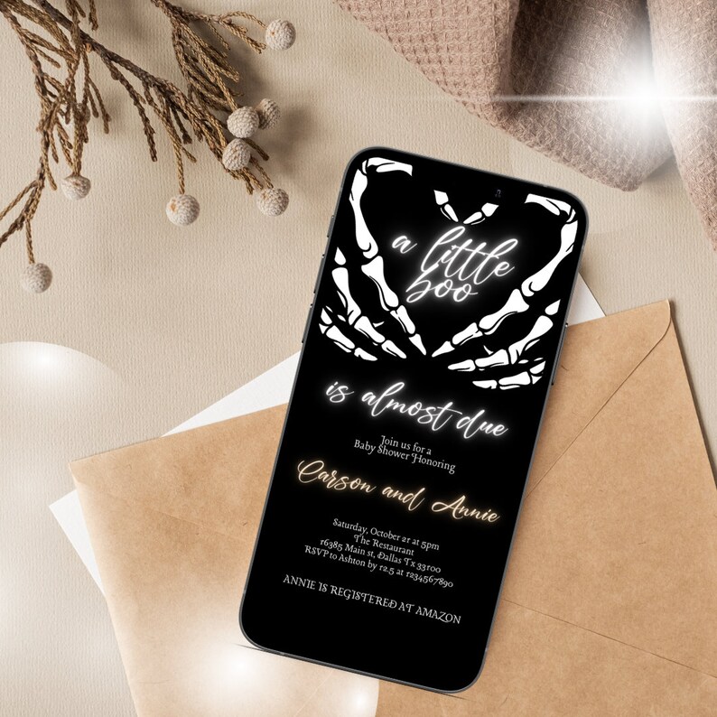 May include: A black and white digital invitation for a baby shower. The invitation features a skeleton hand heart with the text "a little boo is almost due". The invitation also includes the names "Carson and Annie" and details for the event.