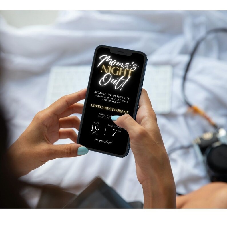 Op de afbeelding: Een zwarte smartphone met een gouden tekstoverlay die "Mom's Night Out!" luidt. De tekst eronder luidt "Because we deserve it! Please join us for dinner and drinks at Lovely Restaurant 1345 Main Dallas, TX Reservation is 7 PM June 19 Friday See you there!"