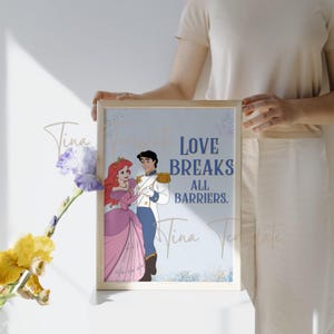 Op de afbeelding: Een blauwe en witte printbare wandkunstprint met Ariel en Prins Eric uit Disney's The Little Mermaid. De print heeft de tekst "Love Breaks All Barriers."