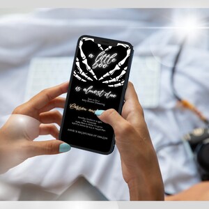 May include: A black and white digital invitation with a skeleton hand heart design. The text reads "a little boo is almost due. Join us for a baby shower honoring Carson and Annie is registered at Amazon."