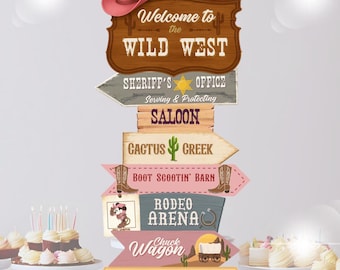 May include: A multi-layered signpost with a cowboy theme. The sign reads "Welcome to the WILD WEST" and features arrows pointing to "SHERIFF'S OFFICE", "SALOON", "CACTUS CREEK", "BOOT SCOOTIN' BARN", "RODEO ARENA", "Chuck Wagon", and "DANGER". A pink cowboy hat sits atop the sign.