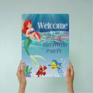 May include: A welcome sign for a birthday party featuring Ariel, the Little Mermaid, with a purple and white text overlay that reads "Welcome to Samantha's Birthday Party".