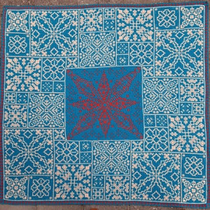 Puede incluir: Una manta de crochet azul con un patrón de copo de nieve blanco. El centro de la manta presenta un copo de nieve rojo más grande.